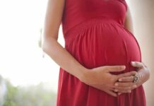 Pregnant woman in a red dress holding her belly