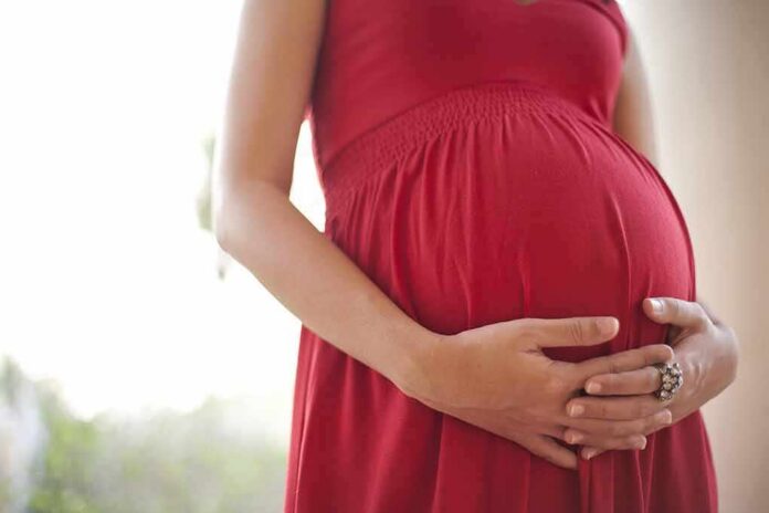 Pregnant woman in a red dress holding her belly