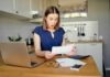 California’s Electric Shock: Double America’s Price Woman in kitchen reacting to a bill at a table with laptop and calculator