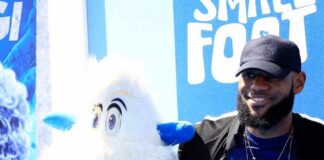 LeBron James posing next to a white yeti mascot at a blue-themed event
