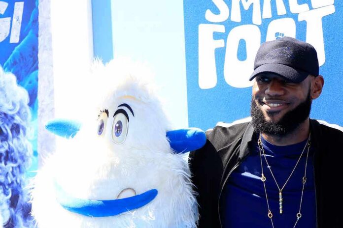 shutterstock_1186703059 LeBron James posing next to a white yeti mascot at a blue-themed event