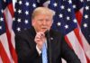 Donald Trump speaking at a podium with American flags in the background