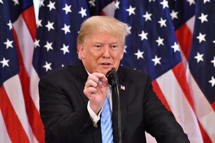 shutterstock_1191272239 Donald Trump speaking at a podium with American flags in the background
