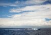 White passenger boat cruising on open sea under cloudy sky