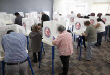 Poll Blitz Aims To Break Republicans Voters fill out ballots at polling booths in a busy voting room
