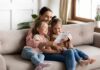 Woman reading a book with two young girls on a sofa