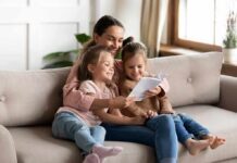 Woman reading a book with two young girls on a sofa