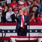 Republicans Put Trump Front and Center Again man in suit points from a stage at a political rally