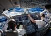 Airline cockpit with two pilots flying over snow-capped mountains