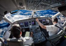 Airline cockpit with two pilots flying over snow-capped mountains
