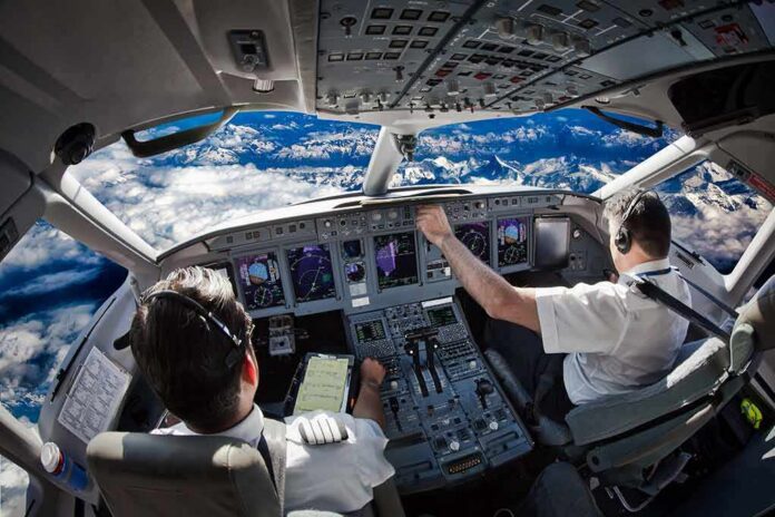 shutterstock_1705305991 Airline cockpit with two pilots flying over snow-capped mountains