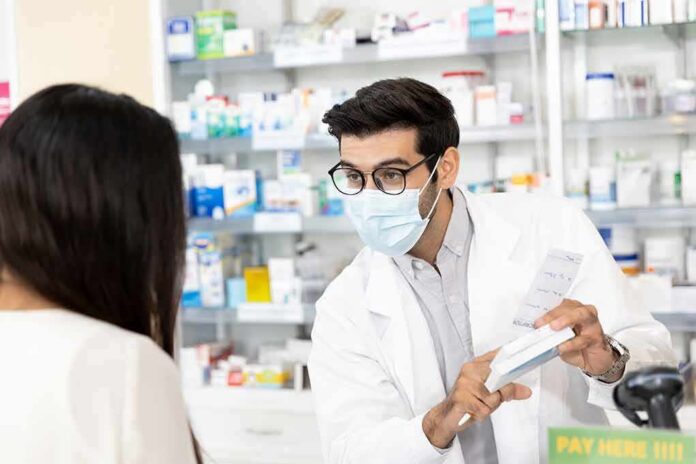 shutterstock_1810030207 Pharmacist wearing mask explains medication to customer