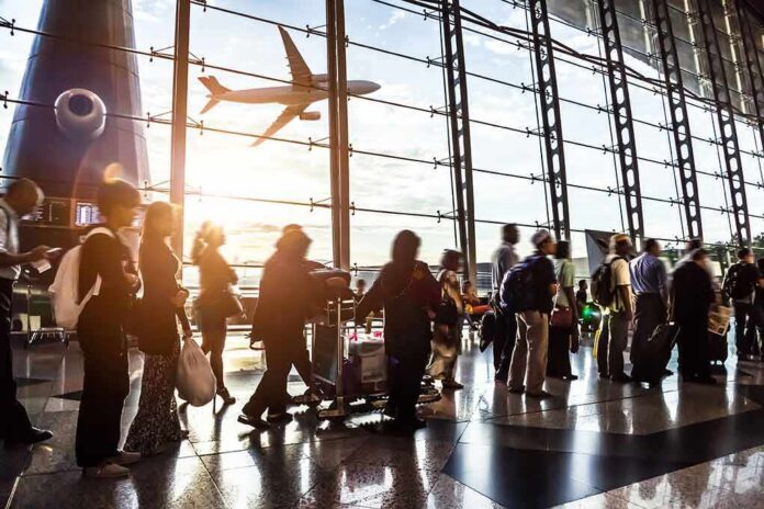 shutterstock_210042967-1 Passengers queue inside an airport terminal at sunset