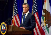 California’s Abortion Shield Just Got Even Bigger Man in suit speaking at a podium with American and California flags