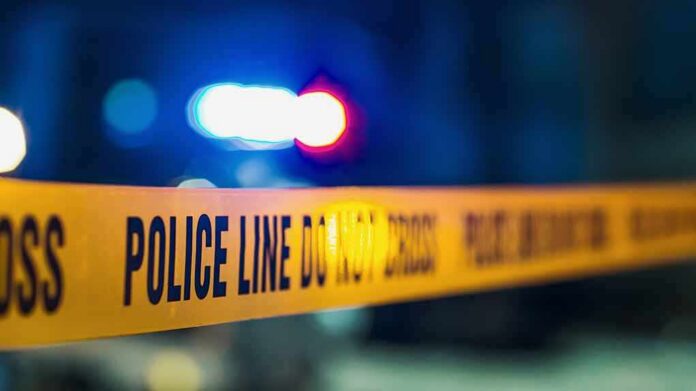 shutterstock_2230644511 Police tape with blurred flashing lights in background