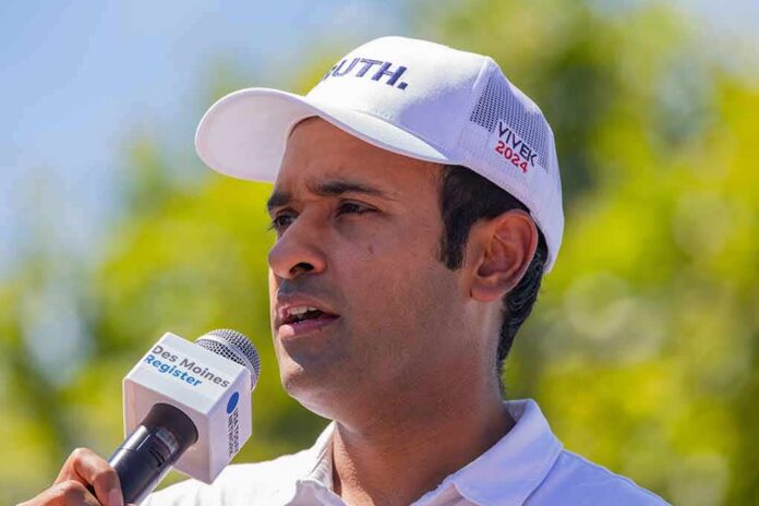 Man in white cap speaking into a microphone outdoors