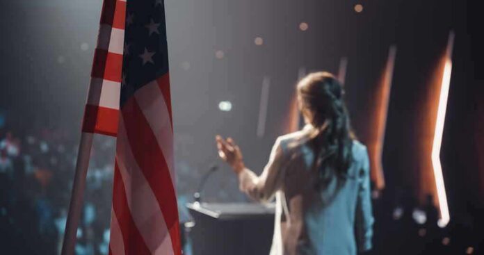 shutterstock_2634227769 American flag and speaker at podium addressing audience