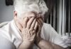 Elderly woman covering her face with her hands