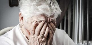 Elderly woman covering her face with her hands