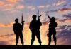 Starvation Siege Strategy Goes Mainstream Silhouettes of three armed soldiers at sunset