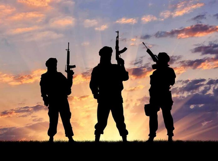 Silhouettes of three armed soldiers at sunset