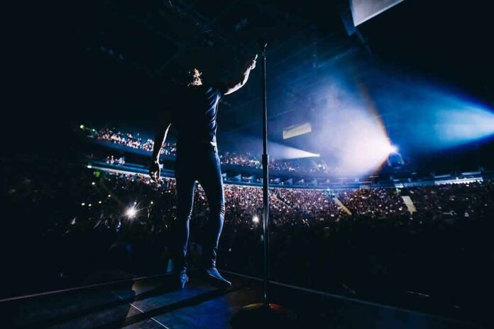 shutterstock_568524262 Singer on stage facing a large concert crowd