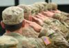 Soldiers in camouflage uniforms saluting in formation