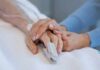 Hands holding in a hospital bed