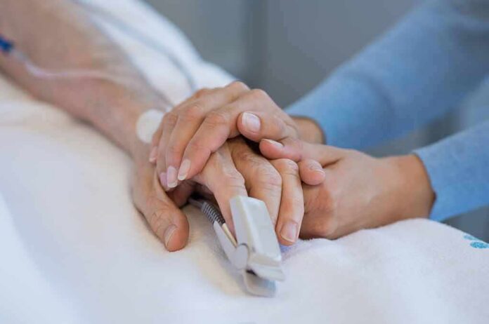 shutterstock_721480087 Hands holding in a hospital bed