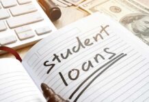 Notebook with student loans written, marker, cash, and keyboard