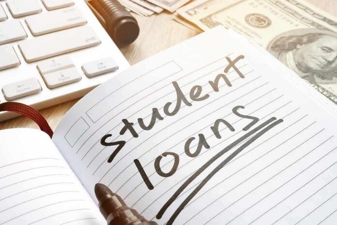 Notebook with student loans written, marker, cash, and keyboard