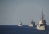 Three naval warships sailing in formation on open sea