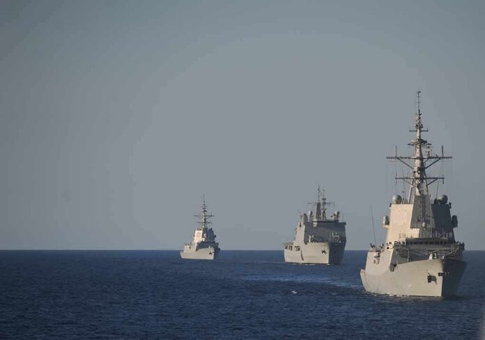 Three naval warships sailing in formation on open sea