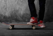 Person standing on a skateboard wearing red sneakers