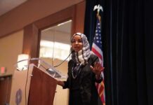 Immigration Crimes Eyed – Omar Probe Deepens Ilhan Omar speaking at a podium with a microphone