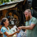 Volunteers distribute relief supplies to a woman outdoors