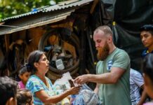 Volunteers distribute relief supplies to a woman outdoors