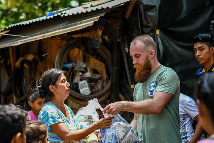 Volunteers distribute relief supplies to a woman outdoors