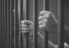 Seven Years Later, a Murder Case Resurfaces hands gripping prison bars