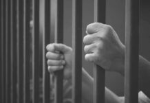 Seven Years Later, a Murder Case Resurfaces hands gripping prison bars
