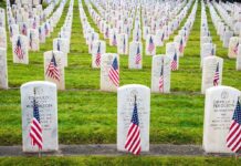 Rows of grave markers adorned with American flags in a military cemetery