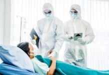 Medical staff in hazmat suits attend to a patient in a hospital bed