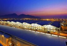 Airport terminal at dusk with illuminated wave-like roof