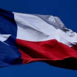 A Statewide Bus Tour Brings A Defiant Message Texas flag waving against a clear blue sky
