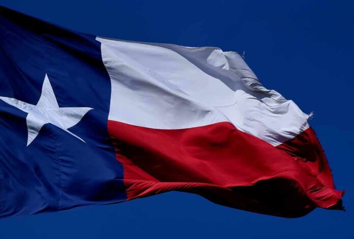 shutterstock_1776979160 Texas flag waving against a clear blue sky