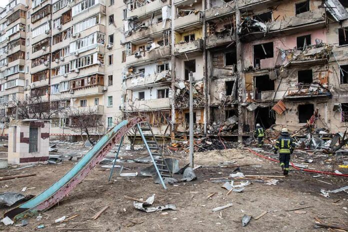 shutterstock_2129012939 Damaged apartment building behind a playground slide