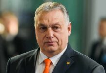 Viktor Orbán in a dark suit with an orange tie at an event
