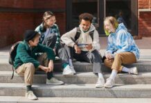 Group of teenagers sitting on outdoor steps looking at a smartphone