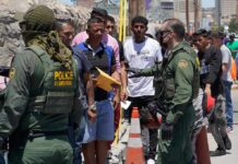 U.S. border patrol officers speak with a line of civilians outdoors