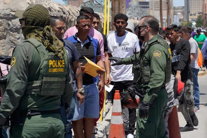 shutterstock_2300859029 U.S. border patrol officers speak with a line of civilians outdoors
